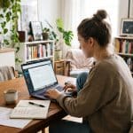 Woman working on a laptop at home while planning a passive income project.